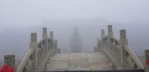 Stone mountain bridge on a misty Buddhist pilgrimage path, symbolizing spiritual thresholds and inner transformation.